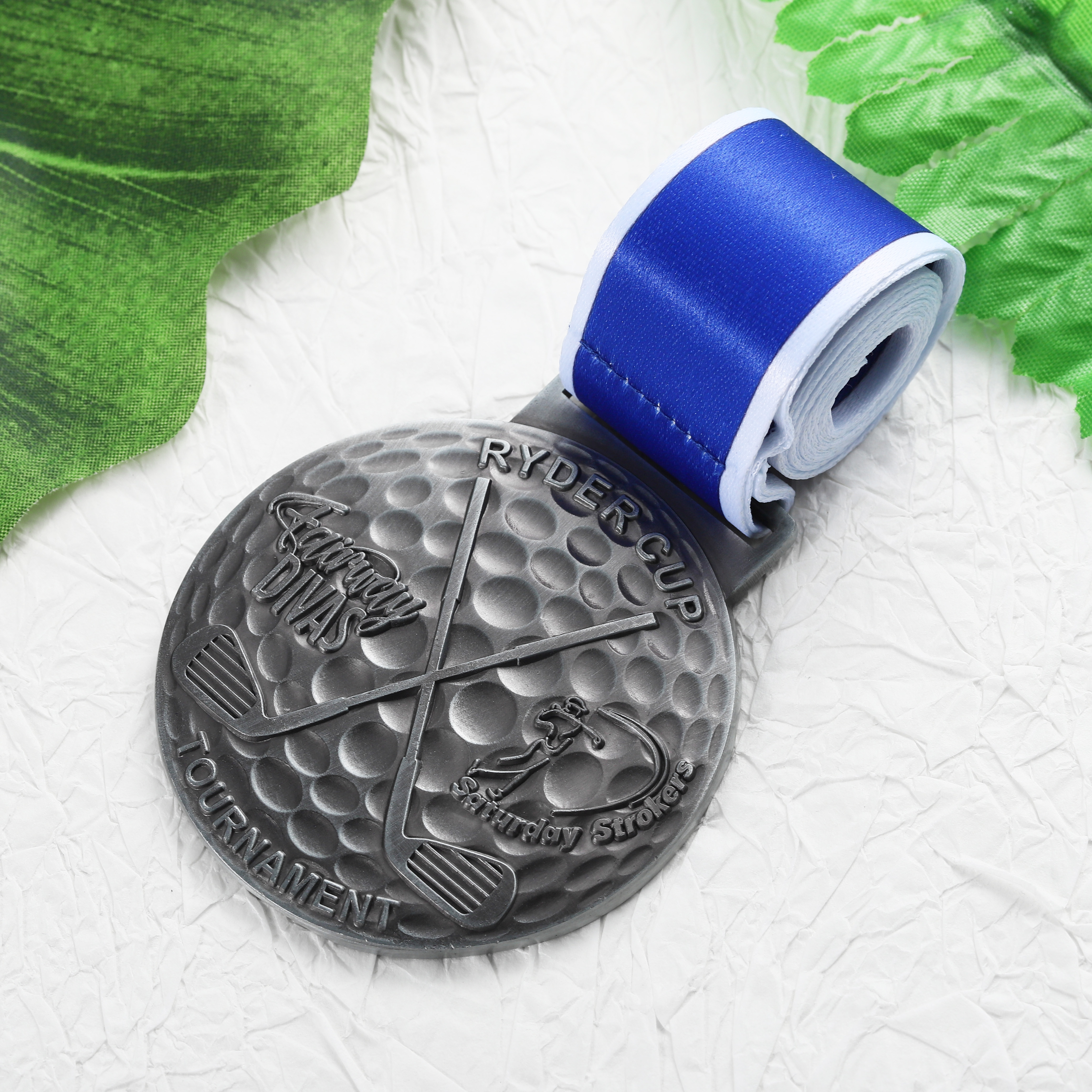 Customizable Low Cost Silver Toned Circular Ryder Cup Golf Medal with Textured Patterns and Blue White Ribbon