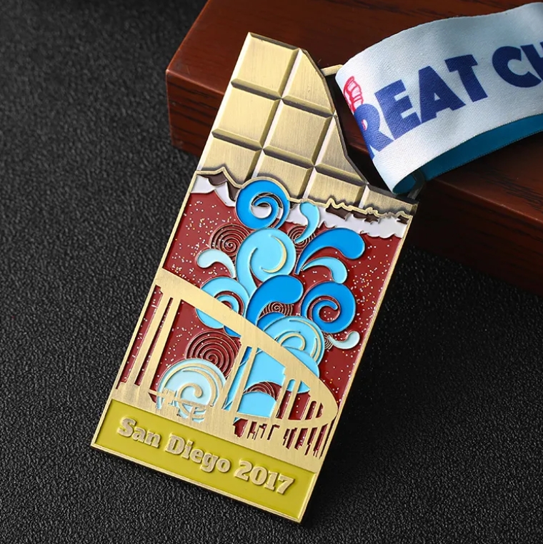 Unique medal shaped like a chocolate bar, with colorful enamel design showing San Diego - themed elements (bridge, waves). Inscribed “San Diego 2017” and paired with a “REAT C” ribbon. Ideal for comme